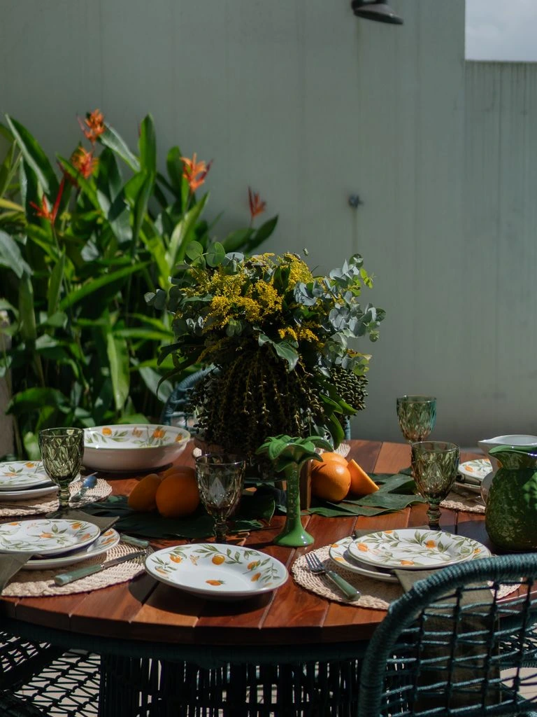 A wooden table set with stoneware and beeswax candles.