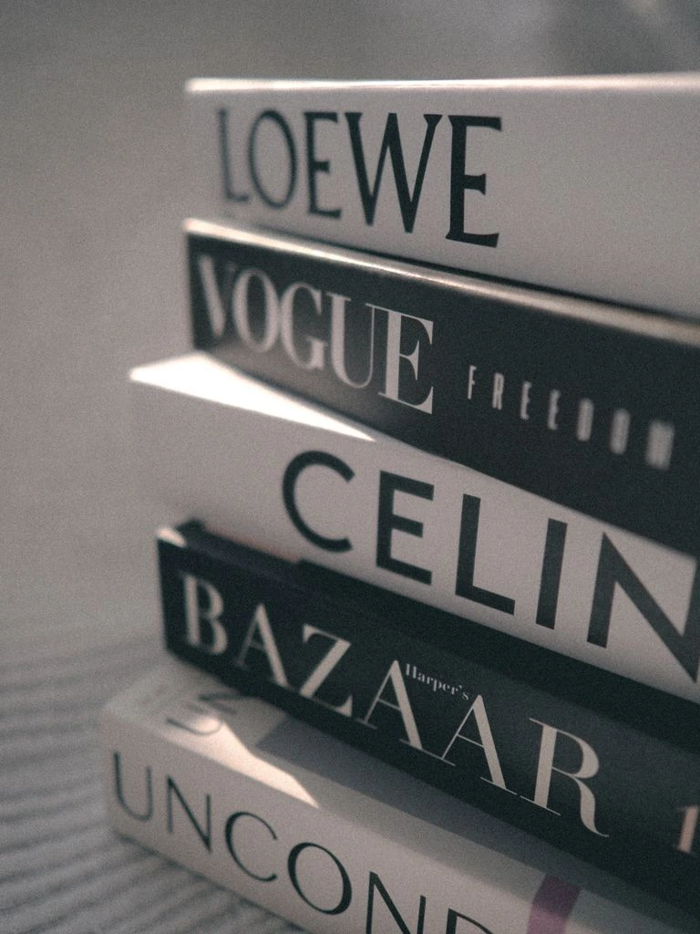 A stack of four hardcovers beside a cup of coffee.
